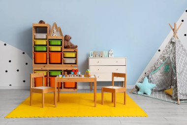 Çocuk odasının içinde masa, çadır ve oyuncaklar var.