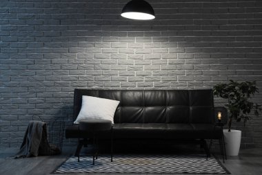 Siyah kanepeli ve parlak lambalı karanlık oturma odasının içi.