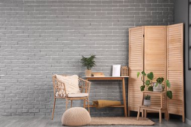 Oturma odası, koltuk, masa ve ahşap perdeli.