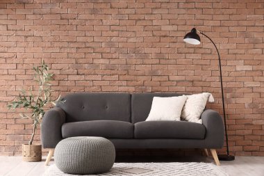 Oturma odasının içinde siyah kanepe, lamba ve puf