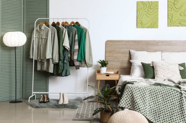 Modern yatak odasının içinde giysi askılığı ve katlama perdesi var.