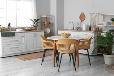 Mutfağın içinde tezgahlar, raf üniteleri ve yemek masası var.