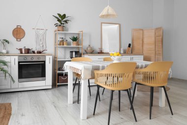 Mutfağın içinde tezgahlar, raf ünitesi ve yemek masası var.