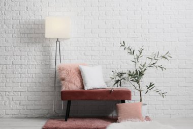 Oda içinde pembe bank, lamba ve zeytin ağacı var.