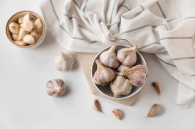 Taze sarımsaklı kaseler ve beyaz arka planda karanfiller.