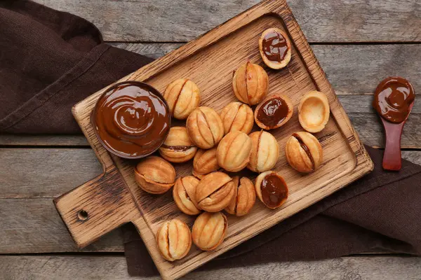 Ahşap zemin üzerinde kaynamış yoğunlaştırılmış sütle ceviz şeklinde kurabiyeler kesme tahtası.