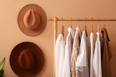 Koridordaki bej duvarda giysiler ve şapkalarla dizilin.