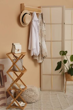 Giysileri, aksesuarları ve katlanabilir ekranı olan şık bir koridorun içi.