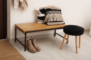 Yastıklı bank, koridorda tabure ve botlar.