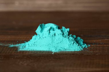 Heap of turquoise powder pigment on wooden table, closeup clipart