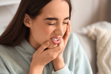 Evde diş ağrısı çeken genç bir kadın, yakın plan.