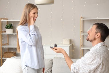 Genç adam mutlu kız arkadaşına evlenme teklif ediyor.