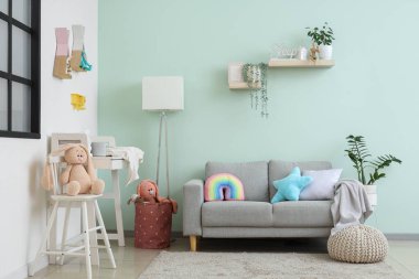 Bebek odasının içinde masa, kanepe ve oyuncaklar var.