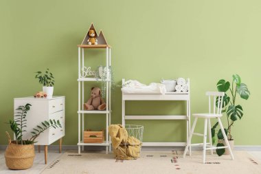 Değiştirme masası, raf ünitesi ve klozeti olan çocuk odasının içi