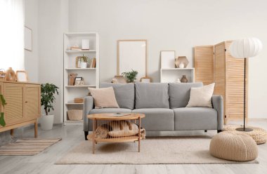 Gri kanepe, lamba ve bitkilerle aydınlık oturma odasının içinde.