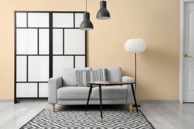 Gri kanepe, lambalar ve katlanan ekran ile oturma odasının içinde.