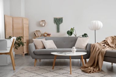 Gri kanepesi, lambası ve masası olan aydınlık oturma odasının içi