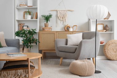 Gri koltuklu, çekmeceli ve lambalı aydınlık oturma odasının içi.