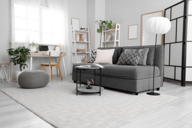 Siyah kanepe, lamba ve işyeriyle aydınlık oturma odasının içinde.