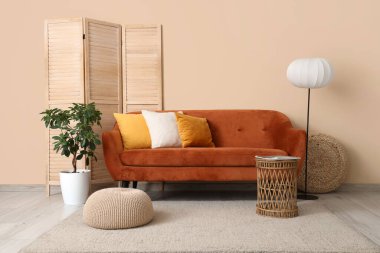 Oturma odasının içinde kırmızı kanepe, lamba ve katlanır ekran var.