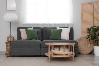 Oturma odasının içinde siyah kanepe, lamba ve masalar.