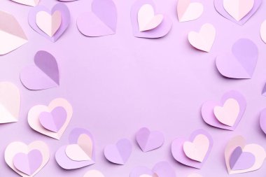 Leylak arkaplanındaki kağıt kalplerden yapılmış çerçeve. Sevgililer Günü kutlaması