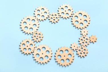 Açık mavi zemin üzerinde ahşap dişlilerden yapılmış çerçeve