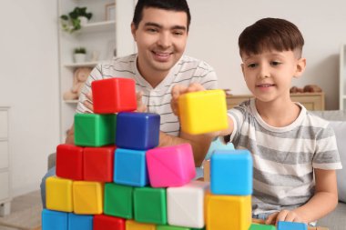 Baba ve küçük oğlu evde renkli küplerle oynuyorlar, yakın plan.