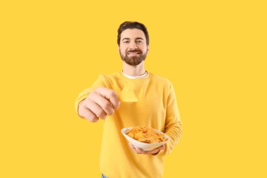 Sarı arka planda lezzetli cipsleri olan bir adam.