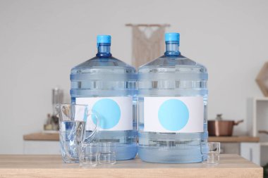 Mutfaktaki masada sürahi ve bardaklarla dolu temiz su şişeleri.