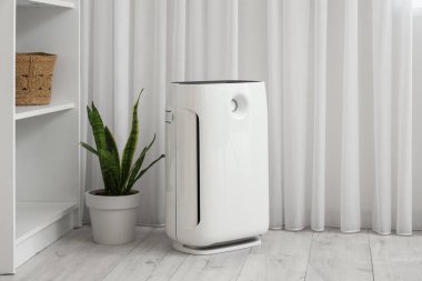 Oturma odasındaki perdenin yanındaki modern hava temizleyicisi.