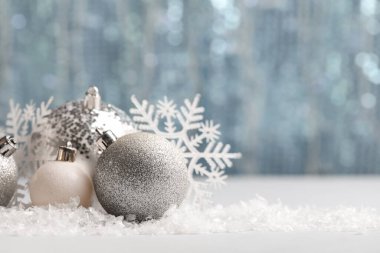 Bulanık ışıklara karşı masasında kar ve kar taneleri olan Noel topları