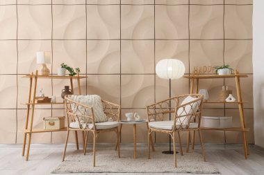 Hasır koltuklu, lambalı ve raf üniteli oturma odasının içi.