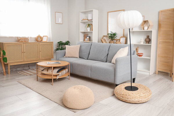 Interior of light living room with grey sofa, lamp and plants