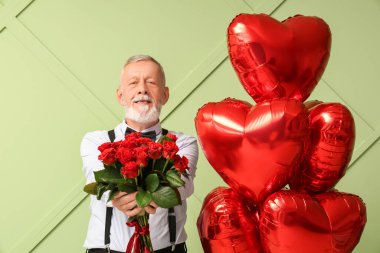 Yeşil arka planda gül buketi ve kalp şeklinde hava balonları olan olgun bir adam. Sevgililer Günü kutlaması
