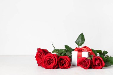 Gri arka planda güzel güller ve hediye kutusu. Sevgililer Günü kutlaması