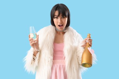 Şok olmuş genç bir kadın ve mavi arka planda bir şişe şampanya. Sevgililer Günü kutlaması