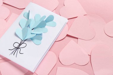 Güzel tebrik kartı ve pembe arka planda kağıt kalplerle kompozisyon, yakın plan. Sevgililer Günü kutlaması