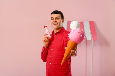 Pembe arka planda soda ve dondurma figürlü genç bir adam. Sevgililer Günü kutlaması