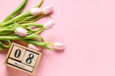 8 Mart tarihli küp takvimi ve pembe arka planda güzel laleler. Uluslararası Kadınlar Günü