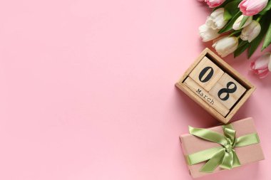 8 Mart tarihli küp takvimi, hediye kutusu ve pembe arka planda güzel laleler. Uluslararası Kadınlar Günü