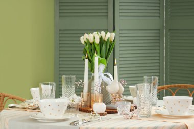 Yeşil duvarın yanındaki Uluslararası Kadınlar Günü kutlamaları için lale çiçekleri ve mum yakılan masa ayarı