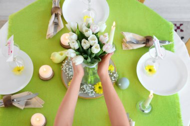 Uluslararası Kadınlar Günü kutlamalarında servis edilen yemek masasında bir buket güzel lale çiçeğiyle kadın elleri.