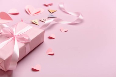 Bej arka planda Sevgililer Günü kutlaması için hediye kutusu ve kağıt kalplerle kompozisyon, yakın plan