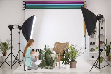 Genç bayan fotoğrafçı, ev bitkileriyle fotoğraf stüdyosunda çekim hazırlığı yapıyor.