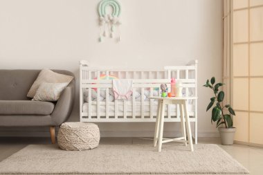 Rahat yatağı ve masanda bebek sütü formülü olan çocuk odasının şık bir iç mekanı.