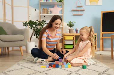 Dadı ve tatlı küçük kız evde küplerle oynuyorlar.