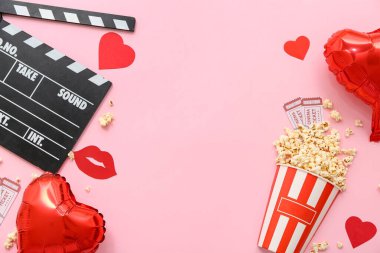 Sinema biletli bir kova patlamış mısır, film alkışları ve pembe arka planda kalp şeklinde balonlar. Sevgililer Günü kutlaması