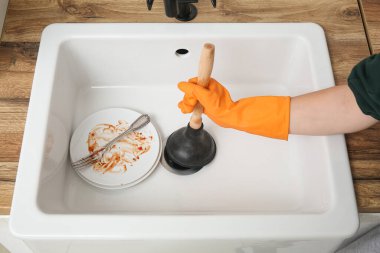 Tıkanmış mutfak lavabosunu pompayla temizleyen kadın, yakın plan.