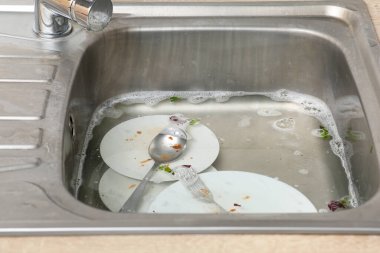 Metallic kitchen sink with dirty dishes, soap water and food leftovers, closeup clipart